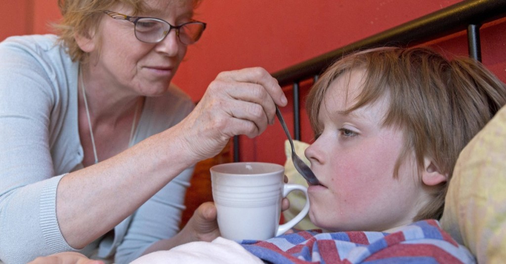 Mutter gibt krankem Sohn Flüssigkeit zum Trinken