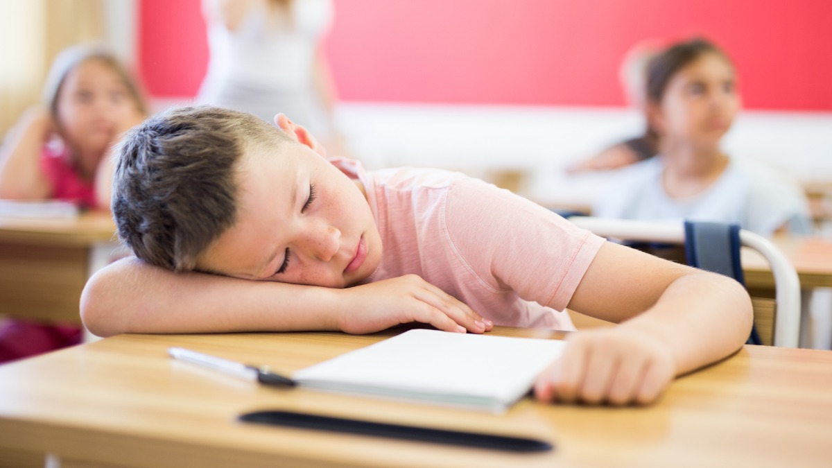 Junge schläft vor Erschöpfung auf dem Schultisch ein