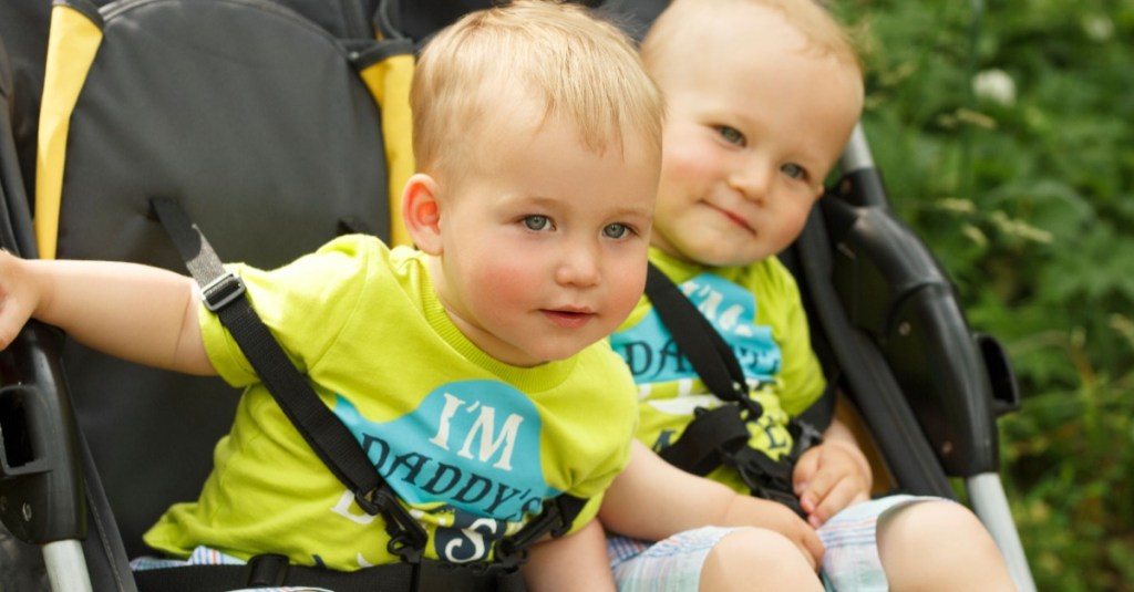 Zwillinge mit gleicher Kleidung im Kinderwagen