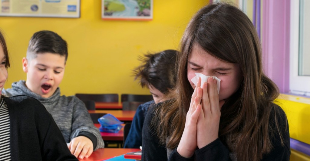 ein Mädchen sitzt in der Schule und putzt sich die Nase