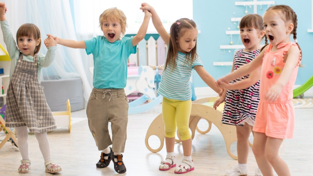 eine Gruppe fröhlicher Kinder tanzt im Kindergarten