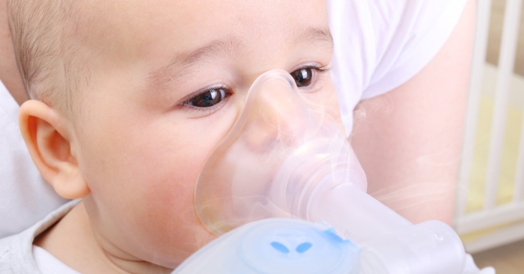 Baby mit einem Inhalationsgerät vor dem Gesicht