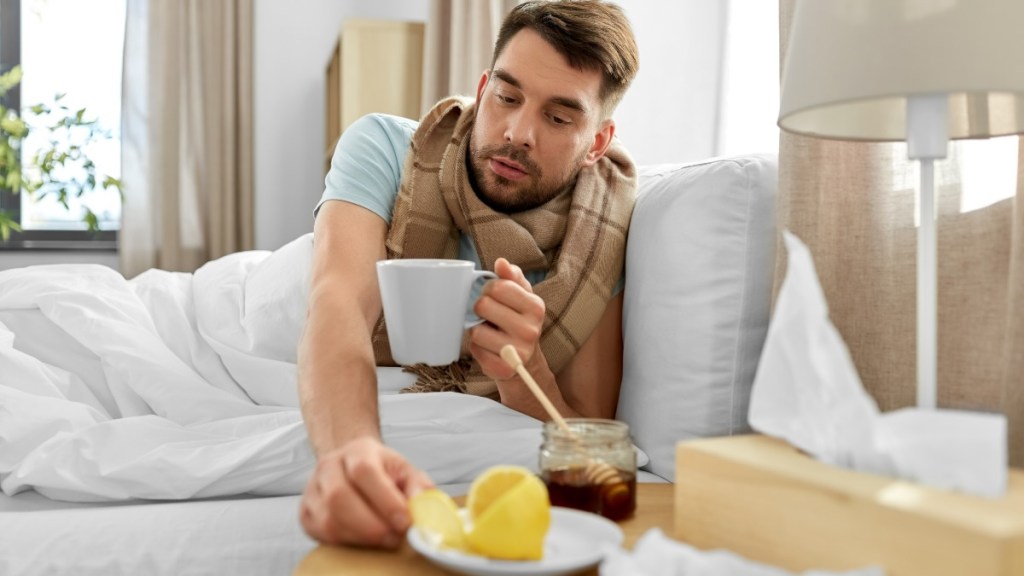 Ein Mann mit einer Teetasse in der Hand greift nach einer Zitronenscheibe.