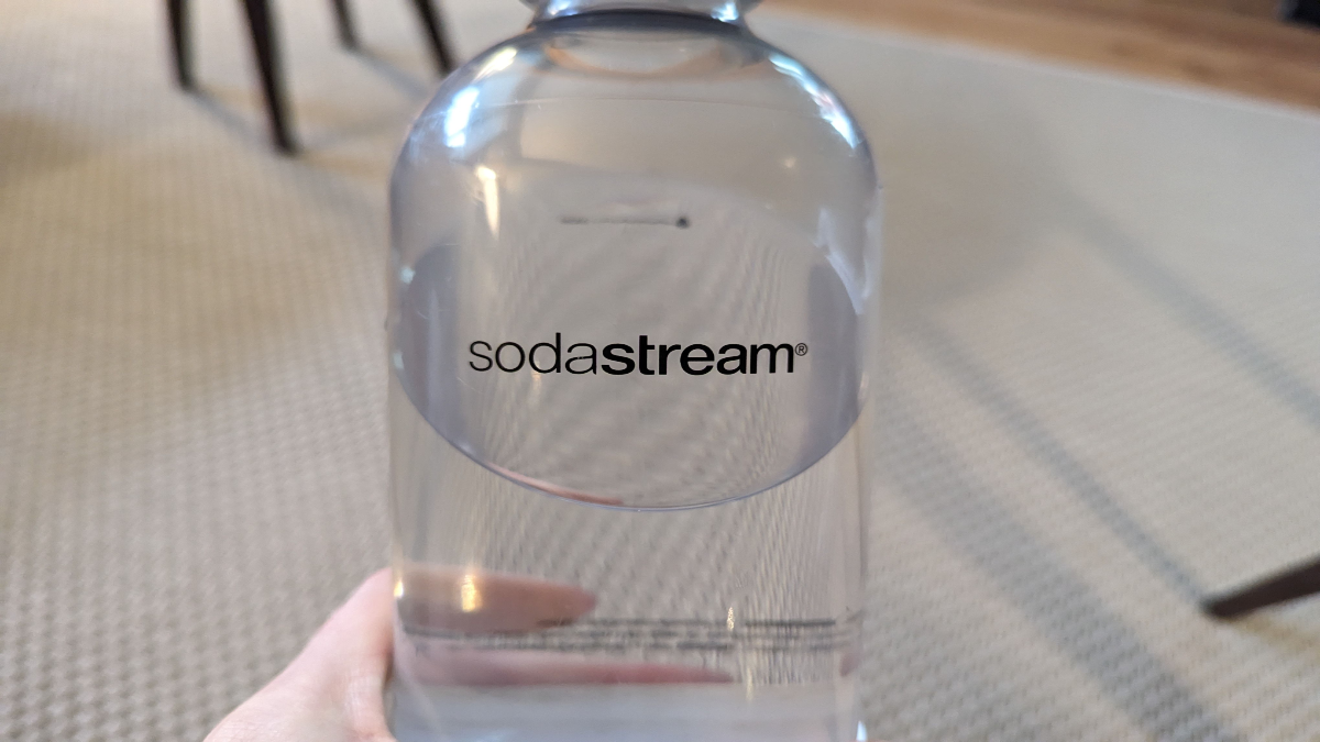 Eine Person hält eine Flasche von SodaStream.