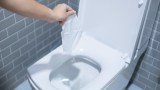 eine Frauenhand hält ein Feuchttuch über eine Toilette