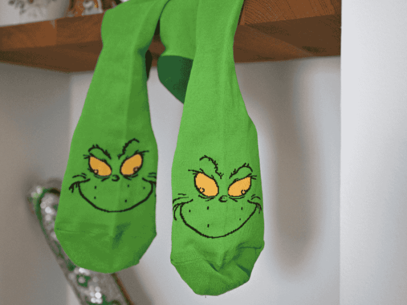 Weihnachtsmuffel, grüne Grinch-Socken hängen vom Regal