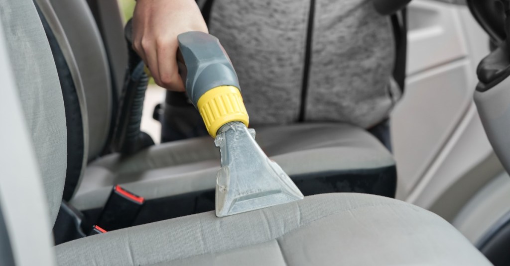 ein Sitz im Auto wird mit einem Nasssauger gereinigt