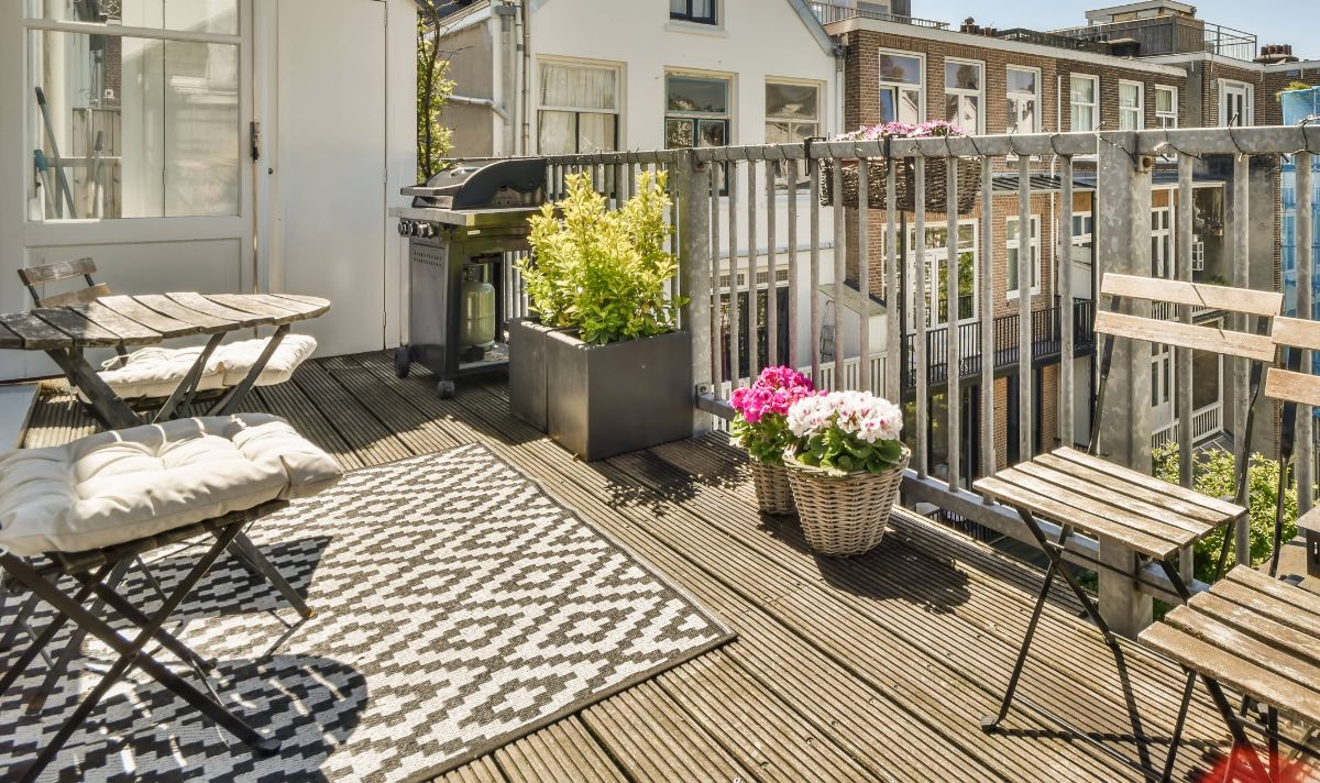 Ein Outdoorteppich auf einem Balkon mit Holzmöbeln und Pflanzen.