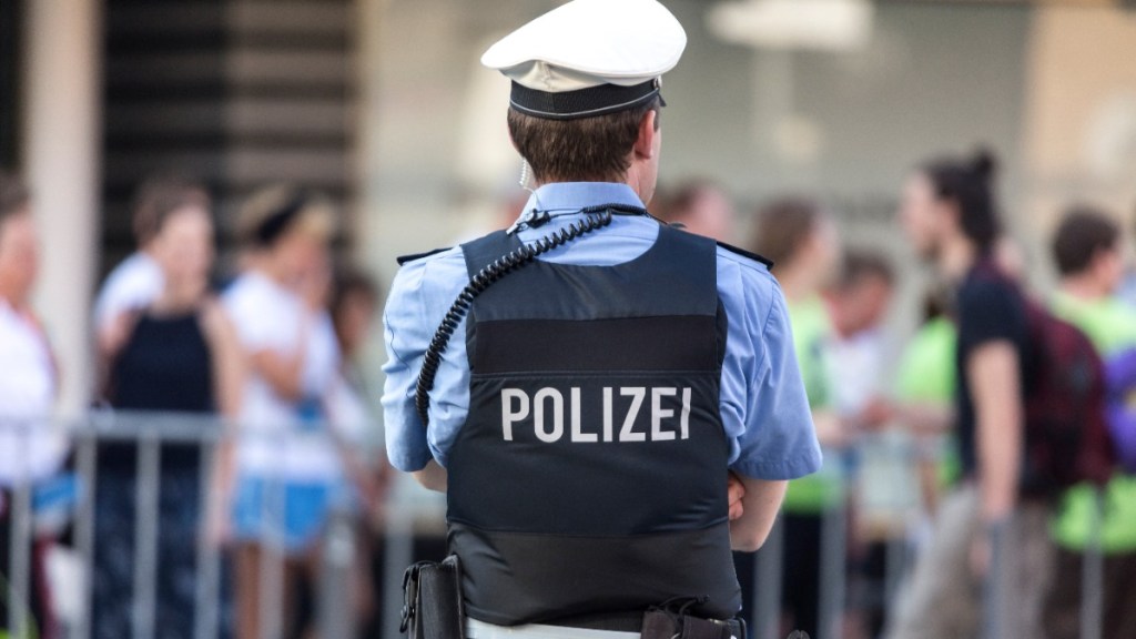 Ein Polizist, der vor einer Menschengruppe steht.