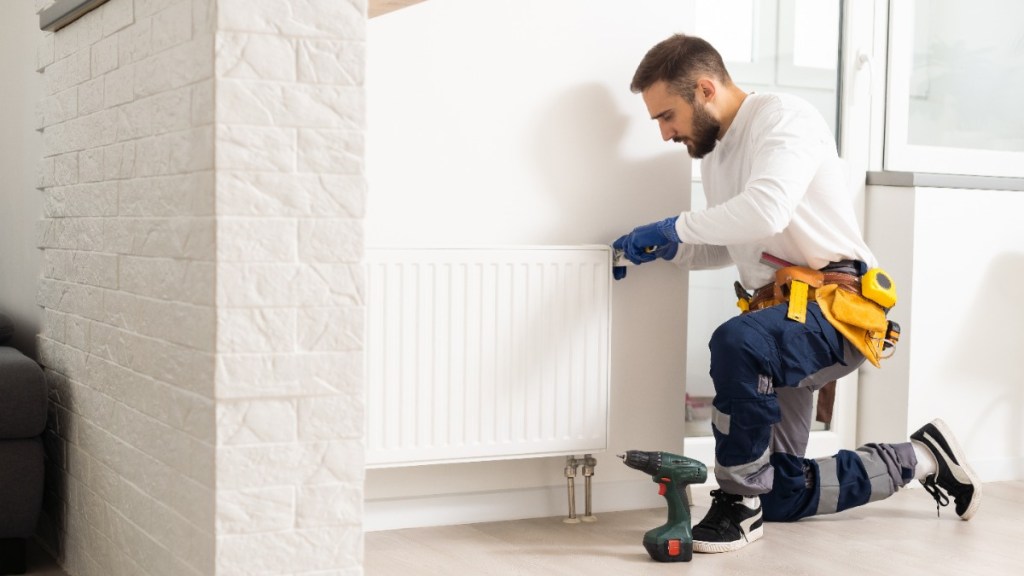 Ein Handwerker, der eine Heizung repariert. 